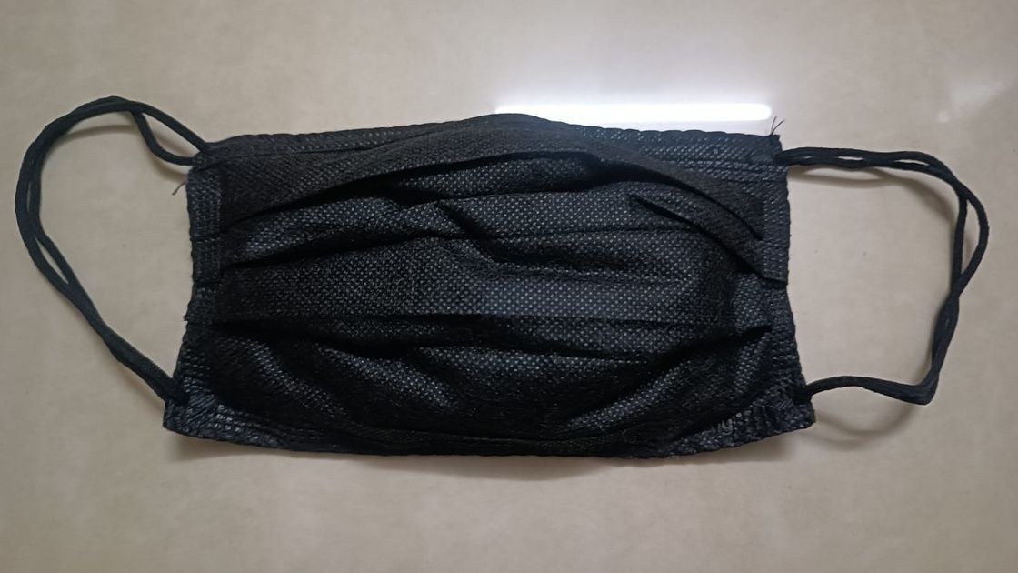 The mask prop: a black face mask laid flat with its ear loops out.